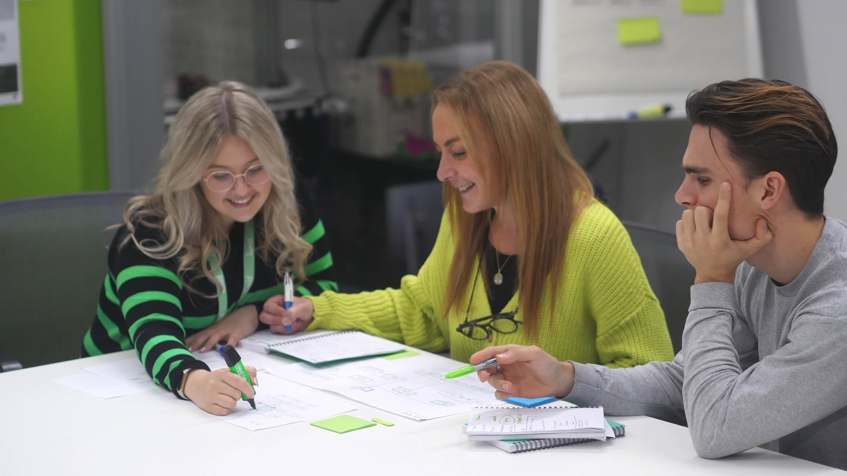 team of 2 women and 1 man brainstorming in office space