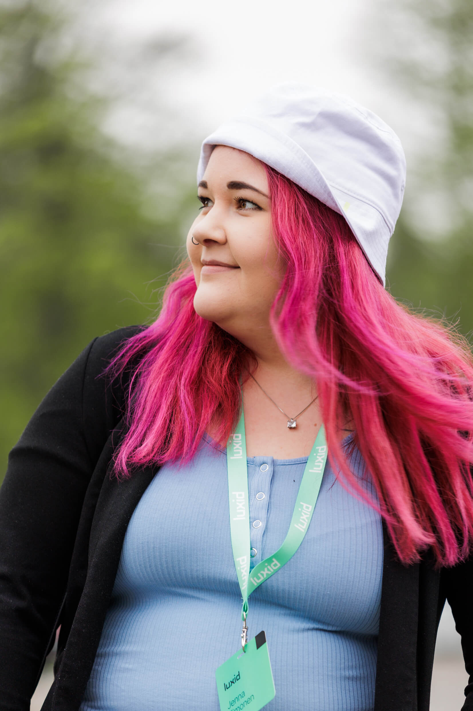 woman with pink hair and white hat looking into the distance