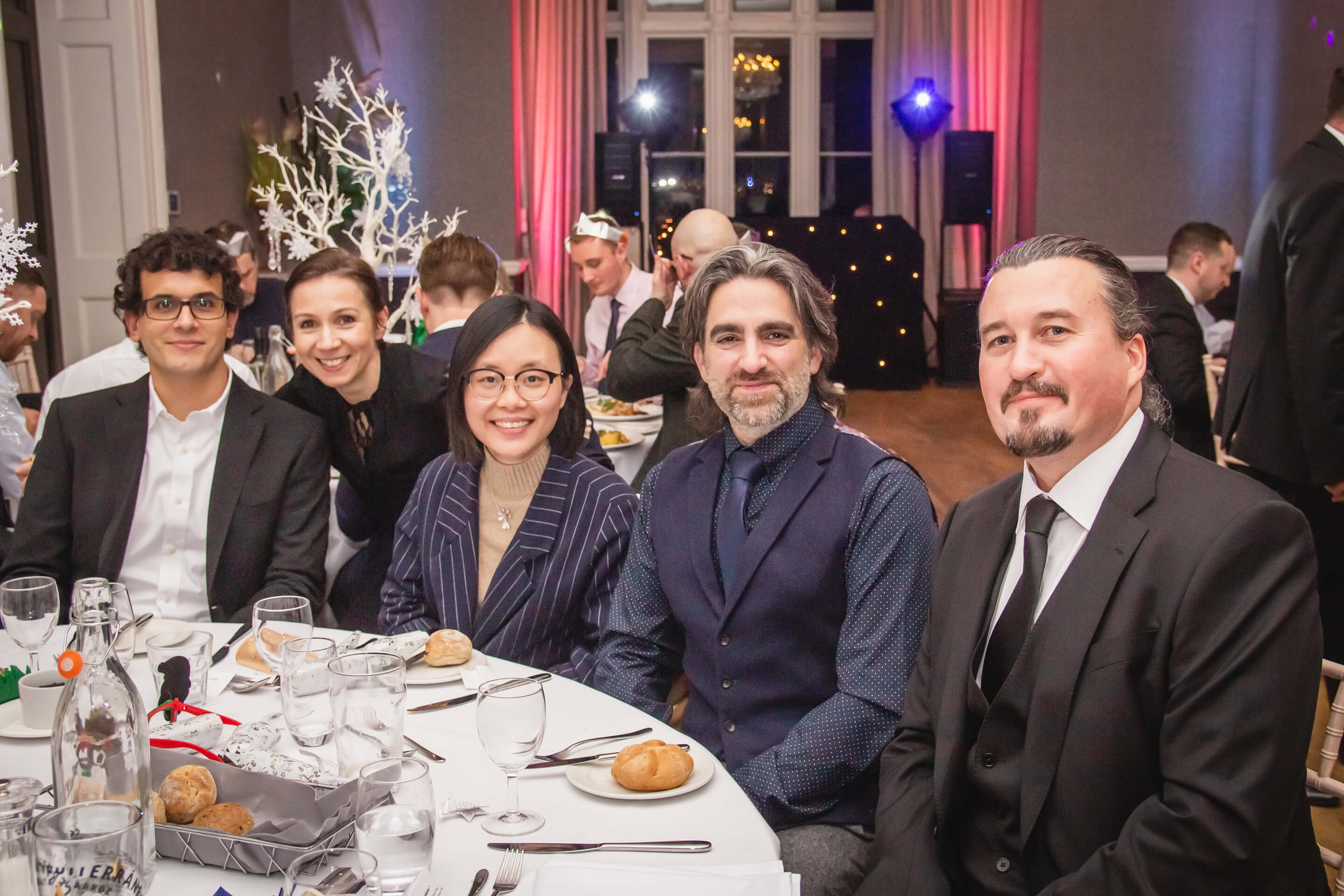 london winter party colleagues sitting around dining table smiling at the camera