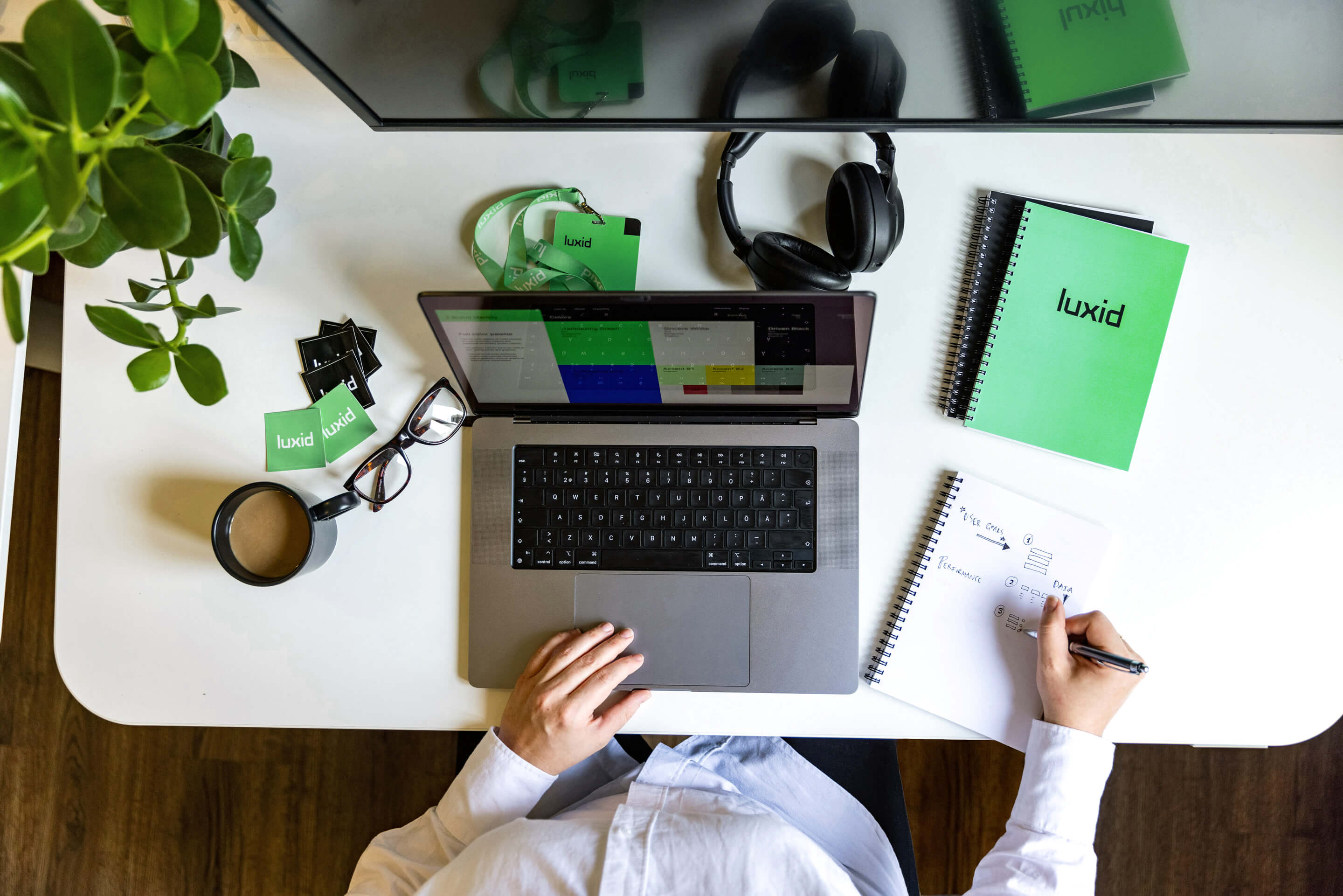 workspace seen from above with desk, laptop, notebooks and coffee mug