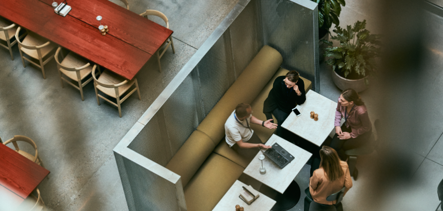 Overhead view of a small group having a meeting in a booth seating area with tables and laptops